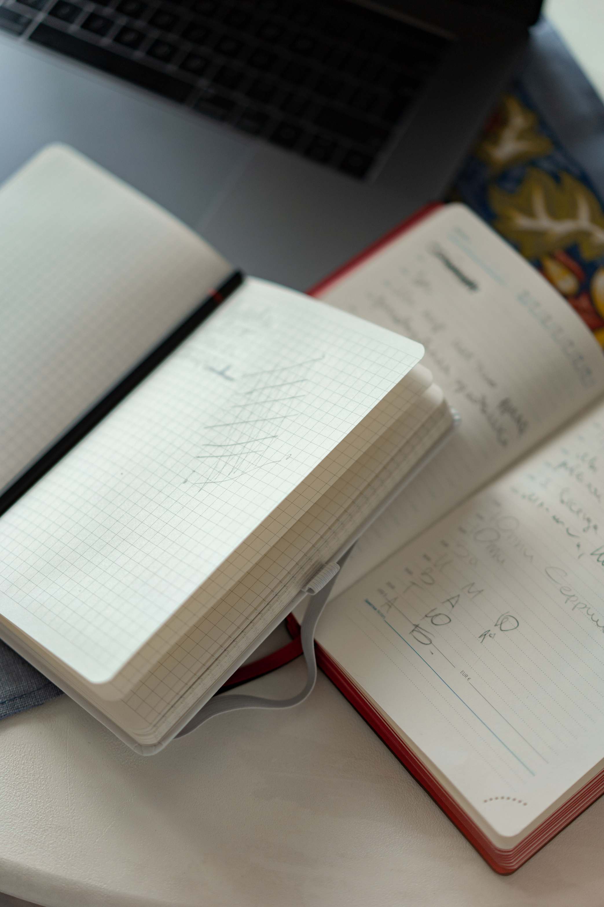 Offene Notizbücher und ein Laptop auf einer weißen Schreibtischplatze